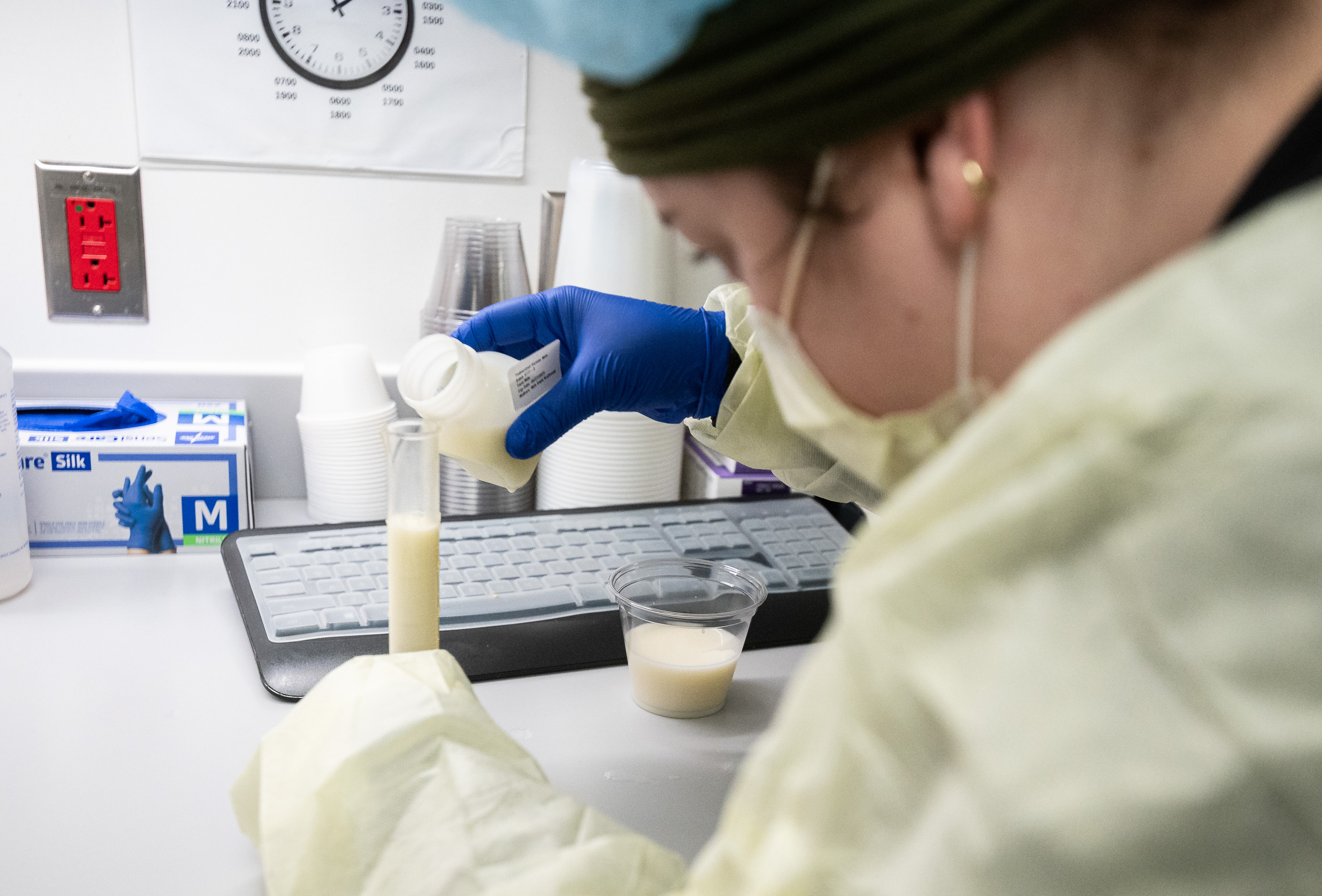 A milk technician carefully pours breast milk into a graduated cylinder to ensure an accurate amount is provided to the patient.