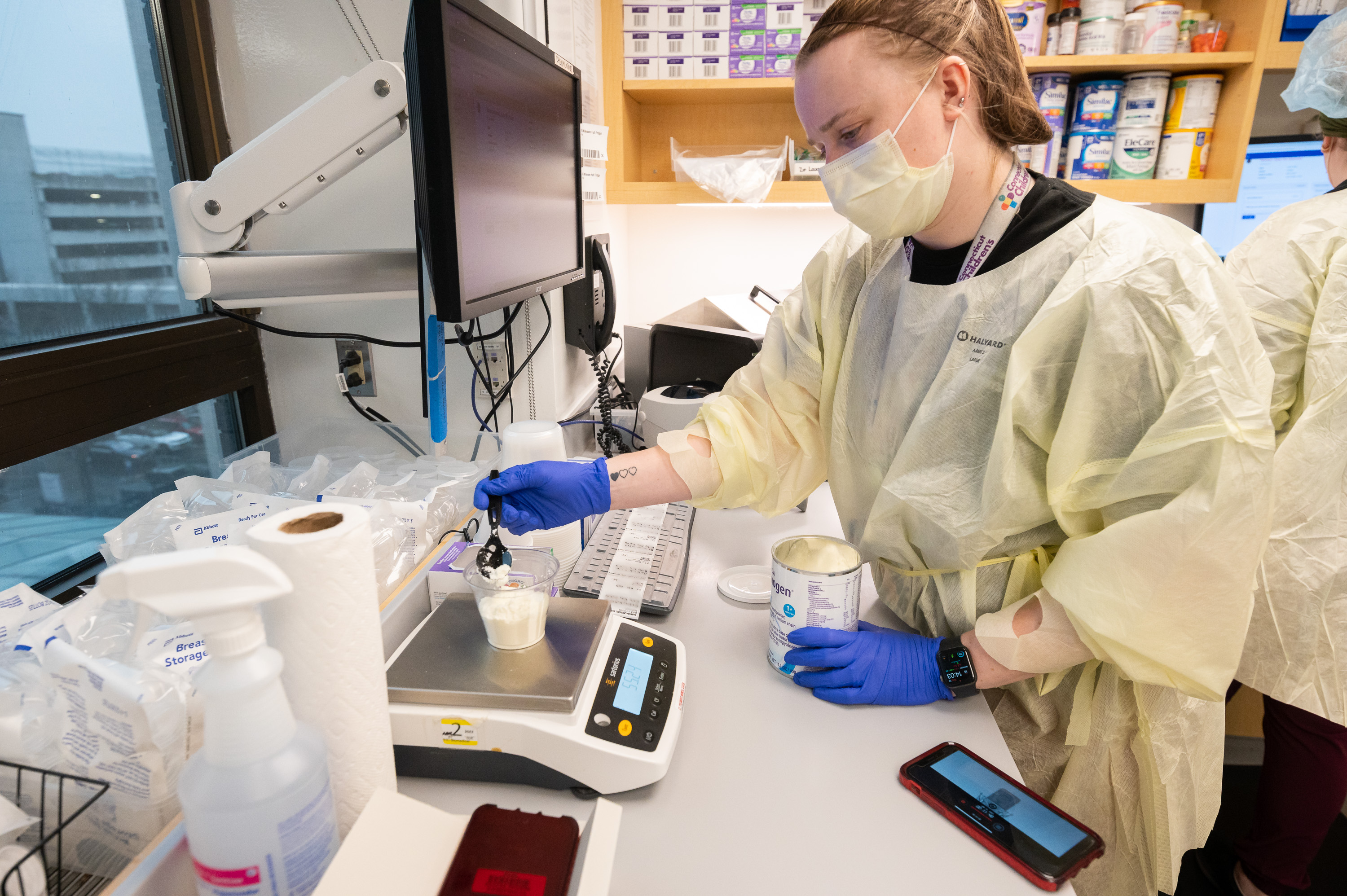 Milk technician Avery Brink measures a precise amount of formula using a digital scale..