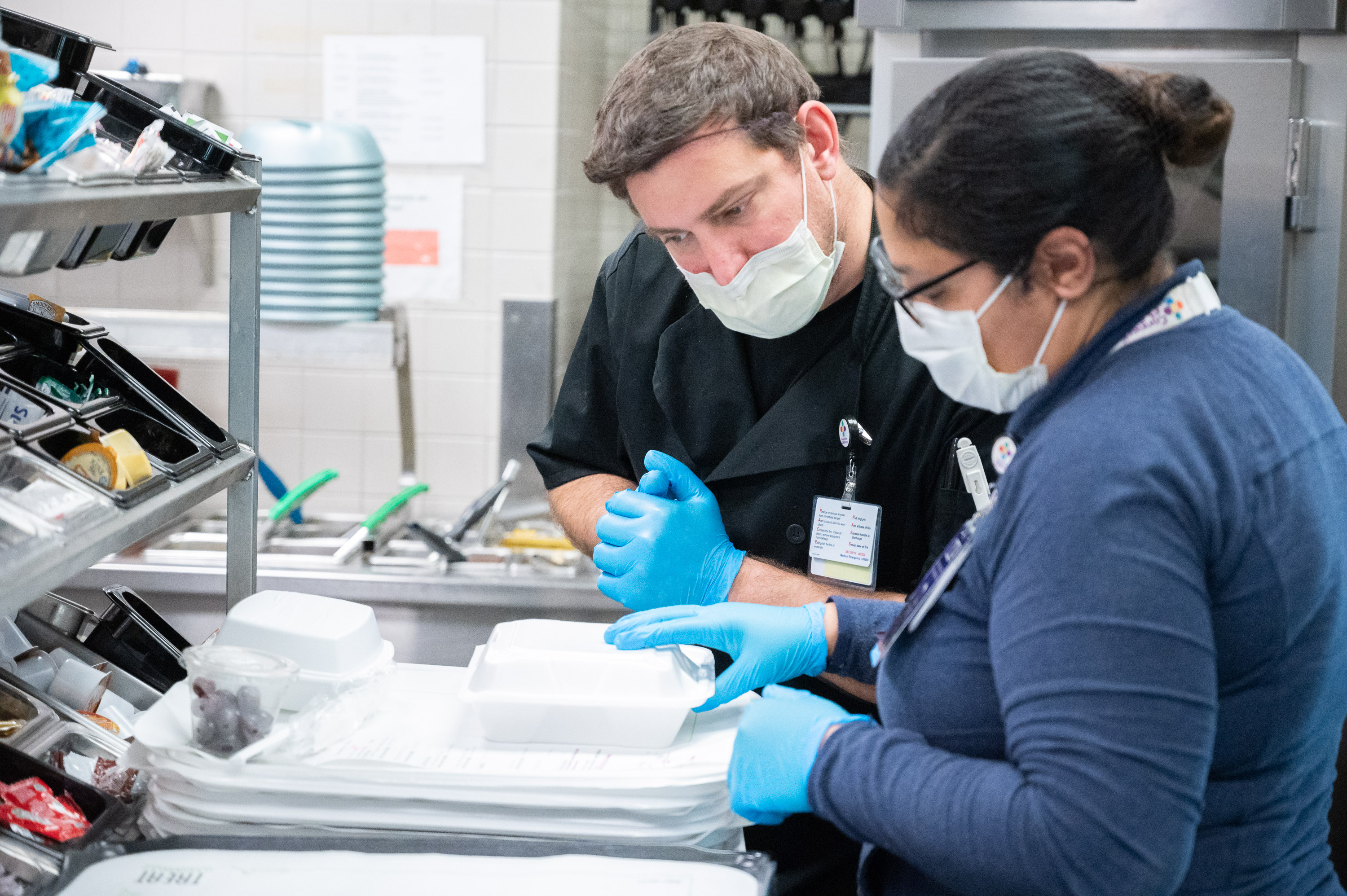 A food services team member consults with a supervisor about a patients meal.