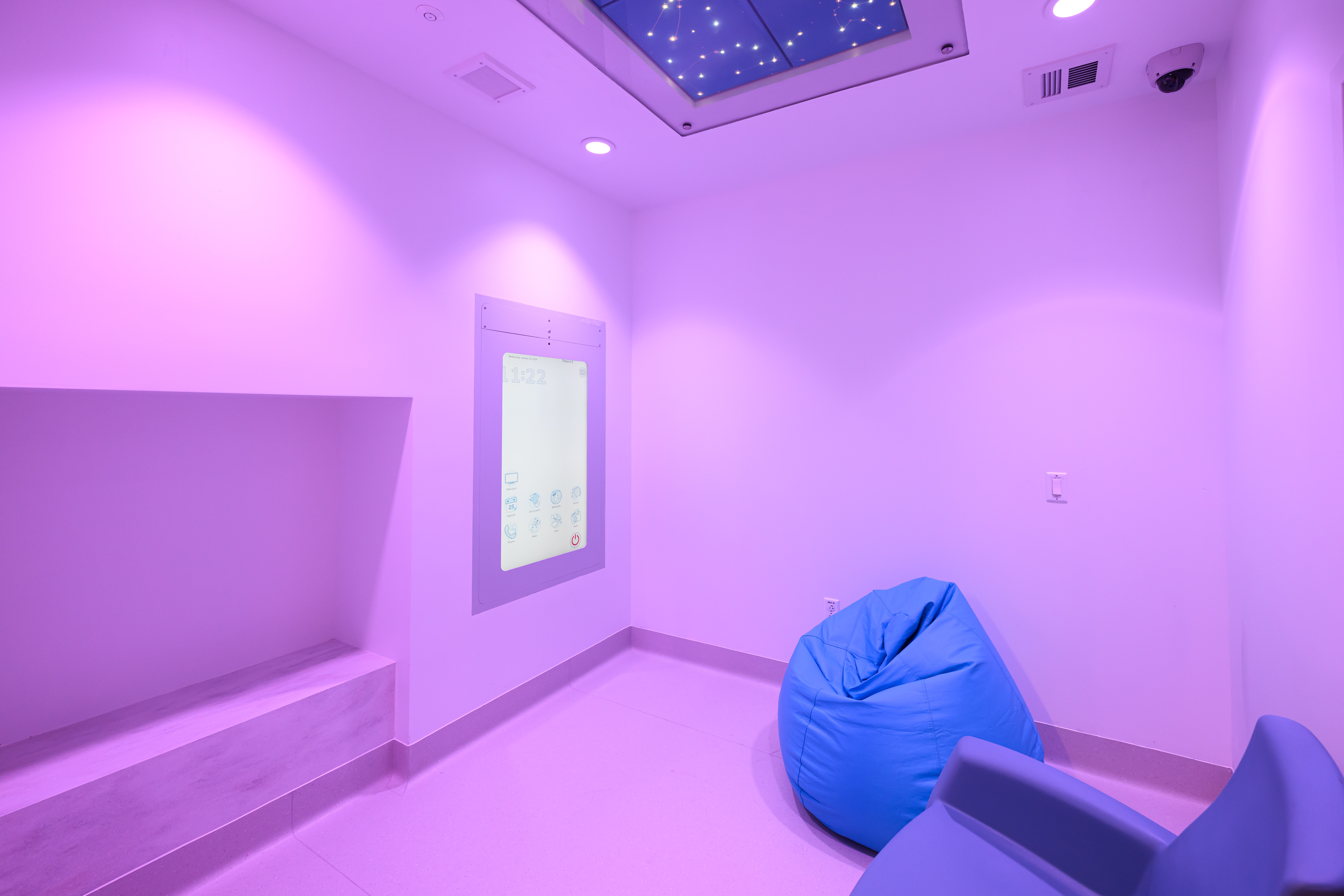 A room featuring a comfy chair and a CoWin Media Wall in the Medical Psychiatric Integrated Care Unit at Connecticut Children's.