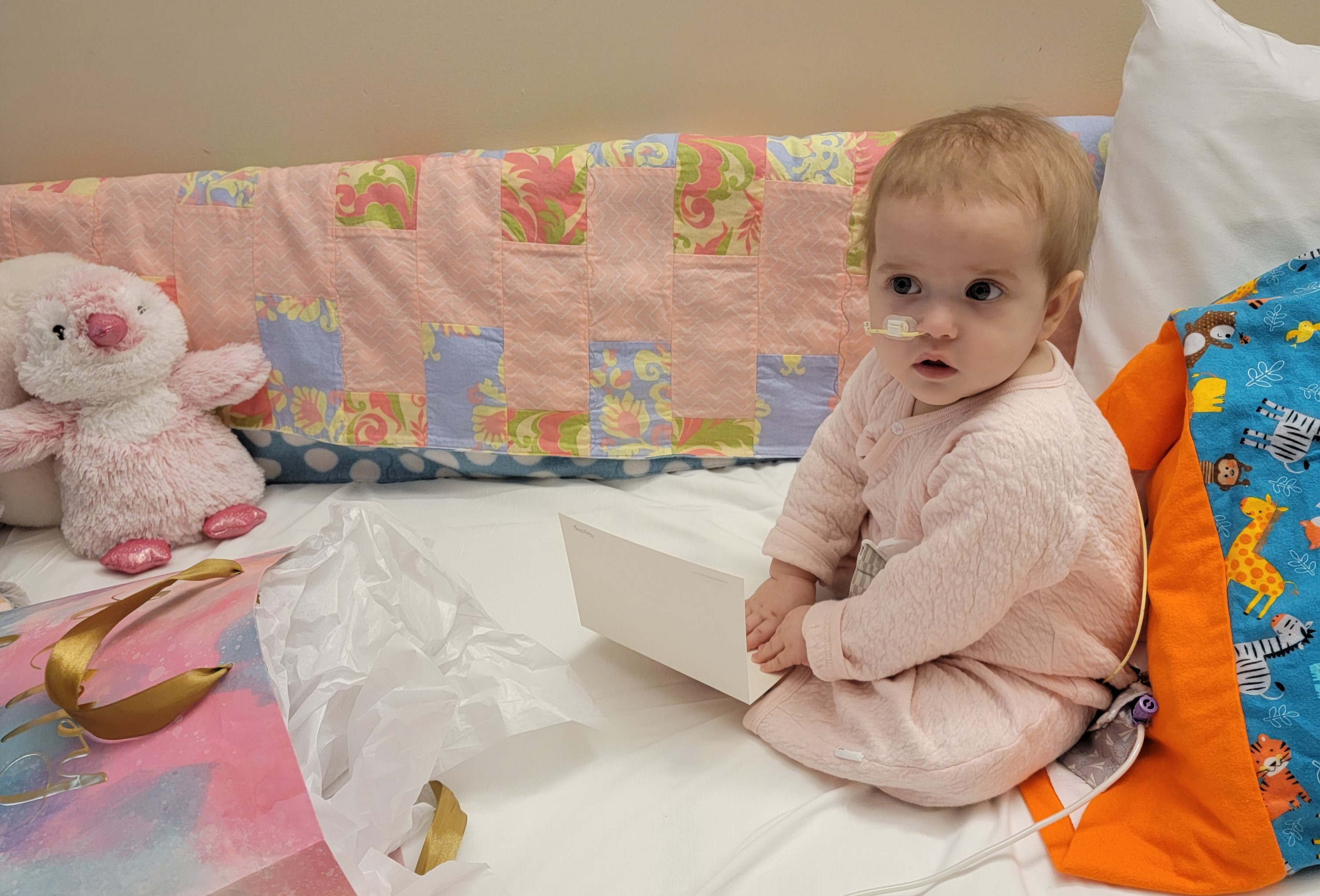 Iliana sits in a crib with a birthday present.