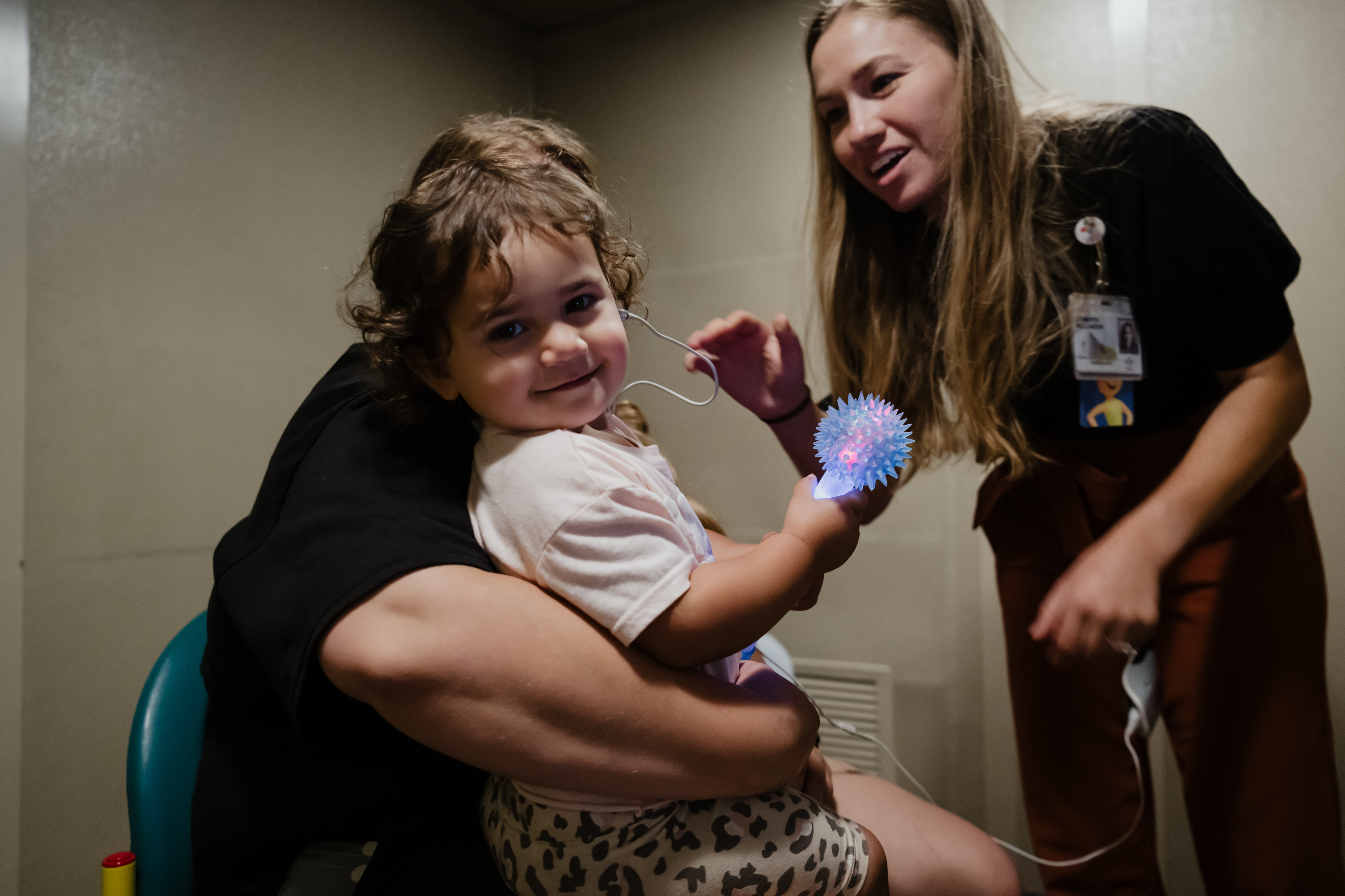 A toddler is seen by Audiology. She holds a distraction toy, provided by Child Life.