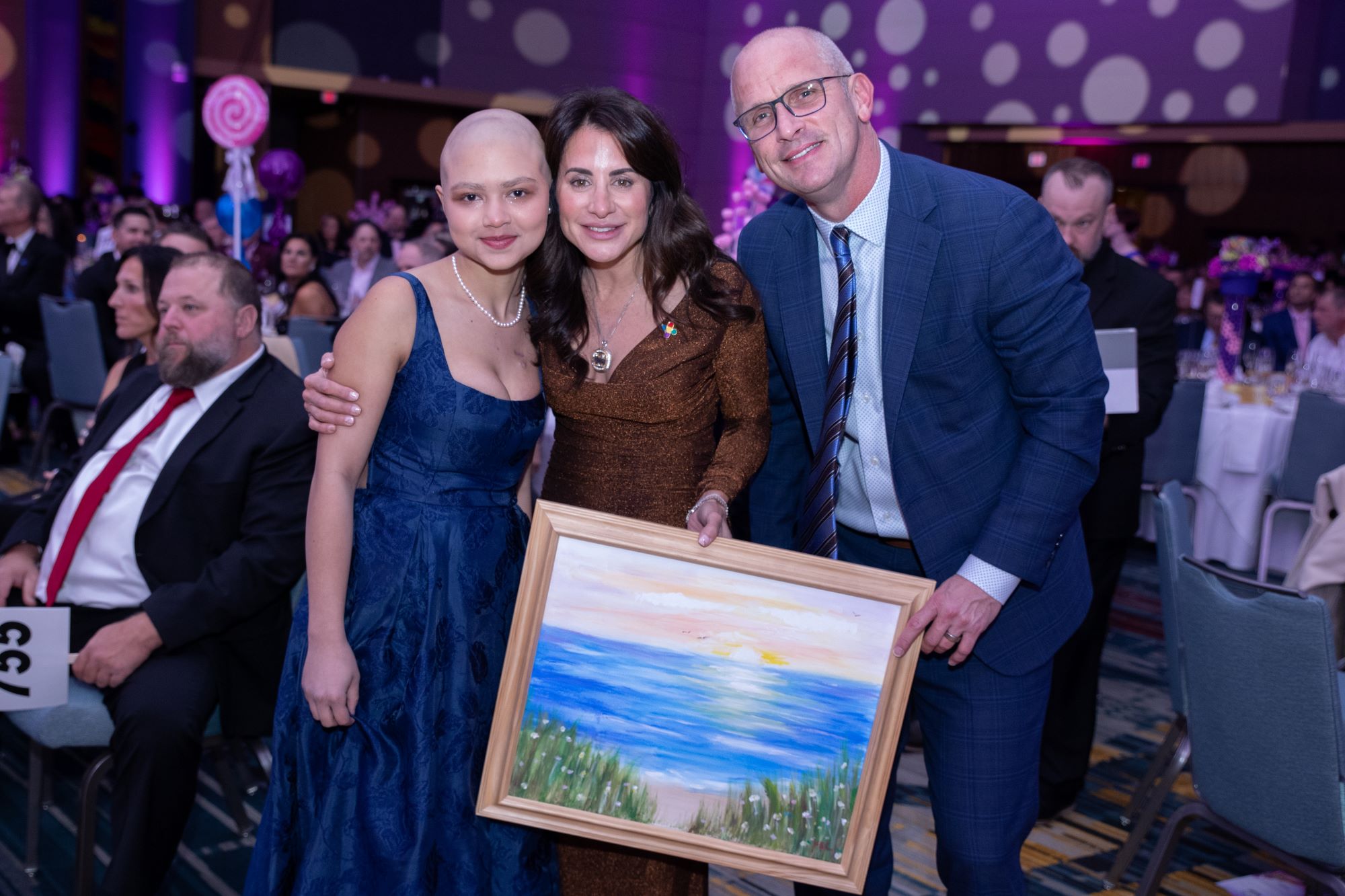 Dan and Andrea Hurley hold their newly won piece or art alongside artist and patient, Ava, who is battling cancer at Connecticut Children's..