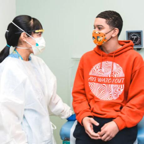 Patient and doctor in an exam room with masks on.