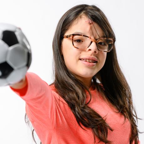 Eliamys stretches out her arm holding a soccer ball