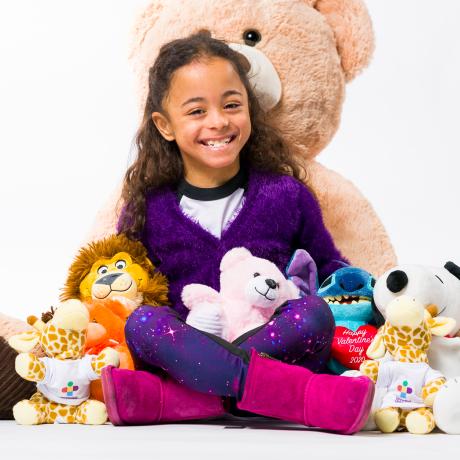 Riley surrounded by stuffed animals