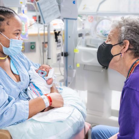 Dr. Sanders speaking with a mother who is holding her infant while in the NICU.