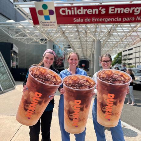 Nurses hold up giant Dunkin' Iced Coffee cutouts to celebrate Dunkin' Iced Coffee Day.